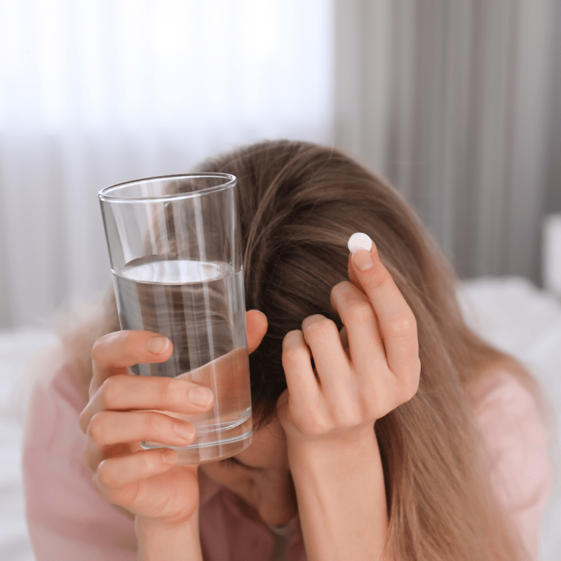 Mujer deprimida tomando pastilla con vaso de agua